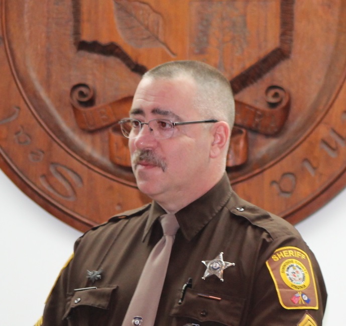 DC Williams standing in front of wooden plaque