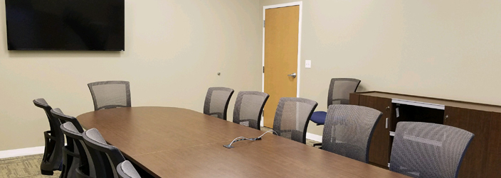 Chairs around a table with a TV screen